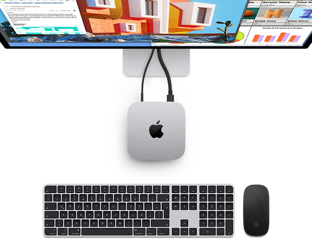 Vista desde arriba de una Mac mini color plata con el logo de Apple conectada a un monitor junto a un Magic Keyboard y un Magic Mouse inalámbricos